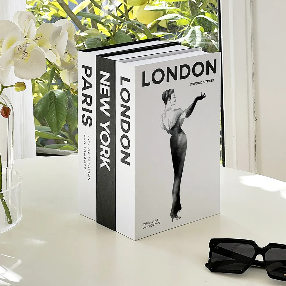 Three books titled 'Paris', 'New York', and 'London' on a table with sunglasses and flowers.