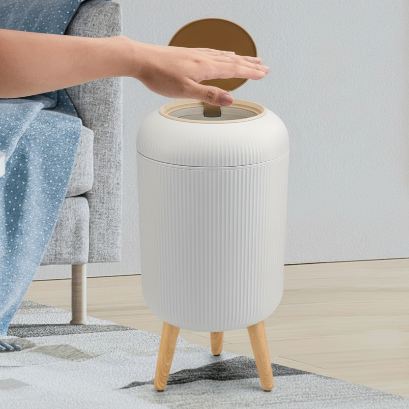 White trash bin with wooden legs on a rug, person using infrared sensing to open lid.